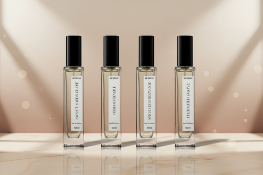 Four perfume bottles with black caps and white labels on a dark background